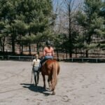 Two women during a horseback riding lesson in an outdoor paddock