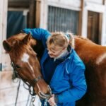 A woman embracing a horse inside a rustic stable