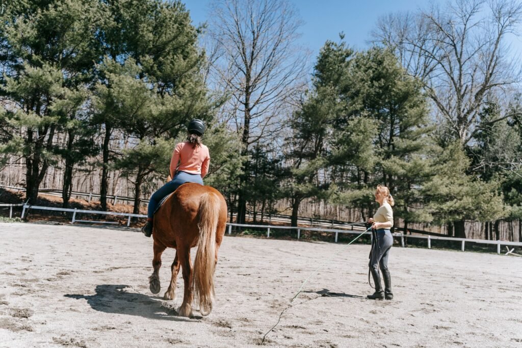 A rider and instructor during a horseback riding lesson in an outdoor arena