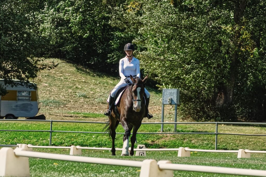 A woman riding a horse in an outdoor dressage arena