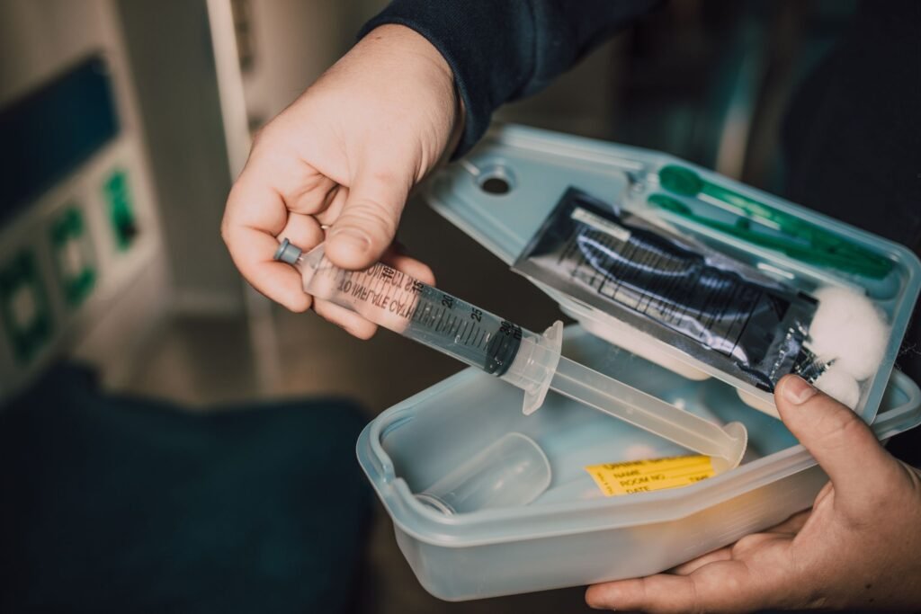 A hand holding a syringe from a medical kit with supplies